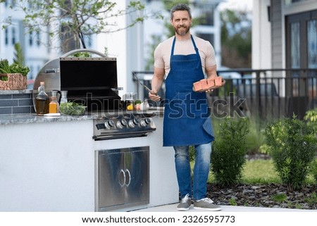 full length of chef man cooking salmon on grill outdoor. grill salmon fish at man wear apron.