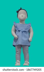 Full length child mannequin dressed in blue dress, isolated on green background. No brand names or copyright objects.