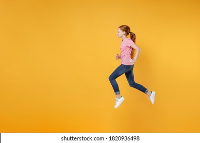 Full Length Children Studio Portrait Side View Of Smiling Little Ginger Redhead Kid Girl 12-13 Years Old Wearing Pink Casual T-shirt Posing Jumping Like Running Isolated On Yellow Color Background