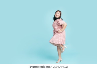 Full Length Confidence Cheerful Beautiful Smile Asian Woman Plus Size In Pink Pastel Dress On Isolate Light Blue Studio Background. Fashion Young Female Chubby Confident Concept.