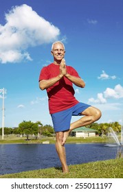 Full Length Of Confident Senior Man Doing Yoga Tree Pose At Lakeshore