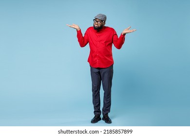 Full length of confused puzzled young bearded african american man in casual red shirt cap eyeglasses standing spreading hands looking camera isolated on pastel blue color background studio portrait - Shutterstock ID 2185857899