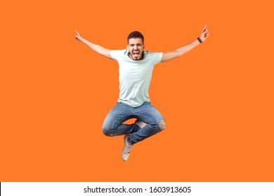 Full length of crazy overjoyed brunette man in white outfit jumping in air with raised hands, screaming loud for joy, feeling energetic and lively. indoor studio shot isolated on orange background - Powered by Shutterstock