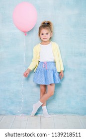 Full length. Cute little girl holding a pink balloon on a blue background.