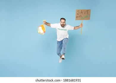 Full length of displeased young man in volunteer t-shirt jumping running hold trash bag placard save planet isolated on blue background. Voluntary free assistance help trash sorting recycling concept