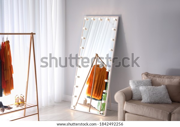 Full length dressing mirror with lamps in\
stylish room interior