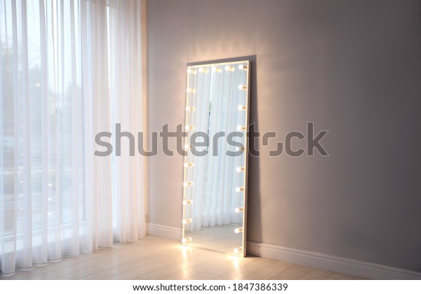Full length dressing mirror with lamps in
stylish room interior