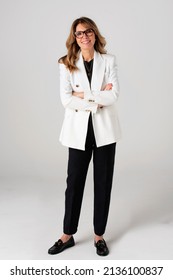 Full Length Of An Elegant Middle Aged Woman Looking At Camera And Smiling While Standing At Isolated White Background.