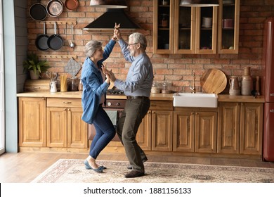 Full length energetic middle aged family couple dancing to disco music in kitchen. Happy old mature man and woman having fun, entertaining together indoors, involved in funny domestic activity. - Shutterstock ID 1881156133