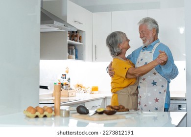 Full length energetic middle aged family couple dancing to disco music in kitchen. Happy old mature man and woman having fun, entertaining together indoors, involved in funny domestic activity. - Powered by Shutterstock