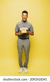 Full Length Of Excited African American Man In Sunglasses And Grey Tennis Shirt Holding Retro Telephone On Yellow