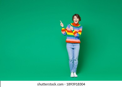 Full Length Of Excited Shocked Young Brunette Woman 20s Years Old Wearing Basic Casual Colorful Sweater Stand Pointing Index Fingers Aside Up Isolated On Bright Green Color Background Studio Portrait