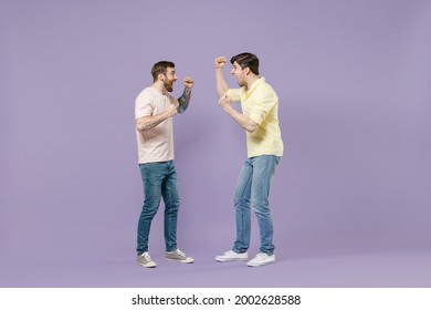 Full length excited two young happy men friends together walk in casual t-shirt walk do winner gesture clench fist look to each other isolated on purple background People friendship lifestyle concept - Shutterstock ID 2002628588