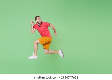 Full Length Excited Young Bearded Man Guy In Casual Red Pink T-shirt Posing Isolated On Green Wall Background Studio Portrait. People Lifestyle Concept. Mock Up Copy Space. Jump Like Run Walk Go Move