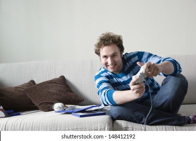 Full Length Of Excited Young Man Playing Video Game On Sofa