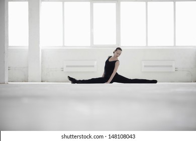 Full length of female dancer doing splits in empty warehouse - Powered by Shutterstock