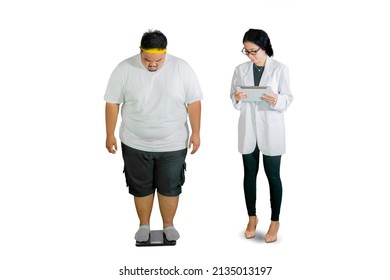 Full length of female doctor holding a digital tablet while checking weight of her fat patient with scale in the studio. Isolated on white background