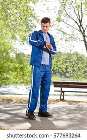 Full length of fit man checking time on path in park
