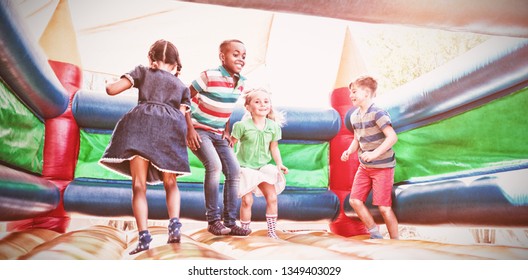 Full length of friends playing on bouncy castle at playground - Shutterstock ID 1349403029