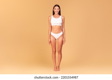 Full Length Frontal View Of Slim Woman With Perfect Body Shape And Flat Tummy Posing On Beige Studio Background, Lady Wearing White Lingerie, Copy Space