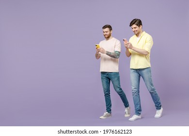 Full length fun smiling two young happy men friends together walk casual t-shirt using mobile cell phone chat online peeps show isolated on purple background studio People friendship lifestyle concept - Powered by Shutterstock