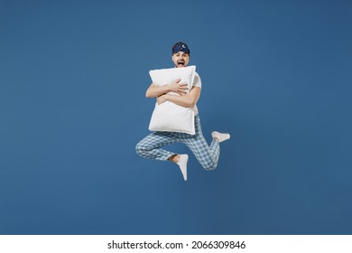 Full Length Fun Young Caucasian Man 20s In Pajamas Jam Sleep Mask Resting Relaxing At Home Jump High Holding Pillow Look Camera Scream Isolated On Dark Blue Background. Good Mood Night Bedtime Concept