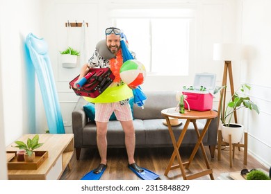 Full length of a funny mid-adult man wearing shorts in the living room preparing to go to the beach during summer vacations