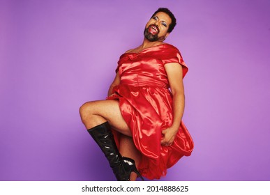 Full length of gay man wearing women clothing dancing and performing in studio. Androgynous male wearing red shiny dress. - Powered by Shutterstock