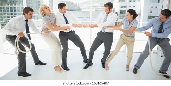 Full Length Of A Group Of Business People Playing Tug Of War In Office