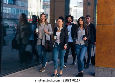 Full Length Of A Group Of Colleagues In Casual Businesswear Discussing Business While Walking At Office Hall