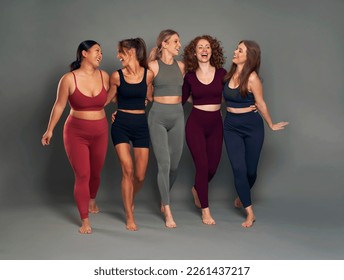 Full length of group of five young women in sports clothes having fun in studio shot - Powered by Shutterstock