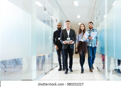 Full length of group of happy young business people walking the corridor in office together - Shutterstock ID 380252227