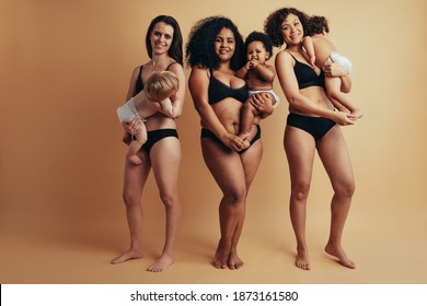 Full Length Of Group Of Three Women Standing Together With Their Babies. Real Bodies Of Women After One Year Of Childbirth.