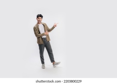 Full length of a handsome asian man pointing out to present something, the smile on his face, his hand gesture and the casual outfit are perfect for the suggestion to copy space. - Shutterstock ID 2203800229
