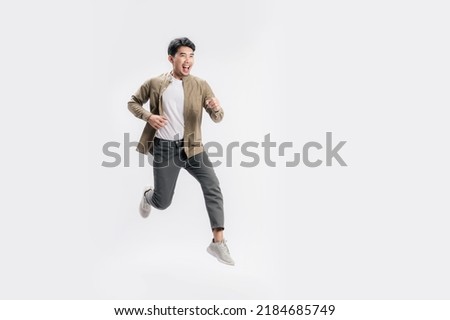 Full length handsome Asian man excited smile he is run in air on isolated white background. Cool man joyful running in copy space. Studio short.