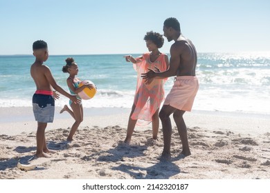 Full Length Of Happy African American Family Playing With Ball At Beach On Sunny Day. Unaltered, Family, Lifestyle, Togetherness, Enjoyment And Holiday Concept.