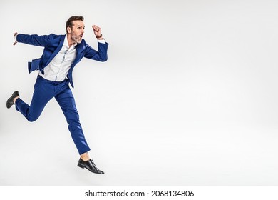 Full Length Happy Business Man In Fashionable Suit Running In Studio. Isolated On Gray Studio Background. Real People Emotions. Freedom. Success.
