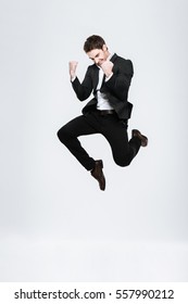 Full length happy business man in black suit jumping and celebrating success isolated on a white background