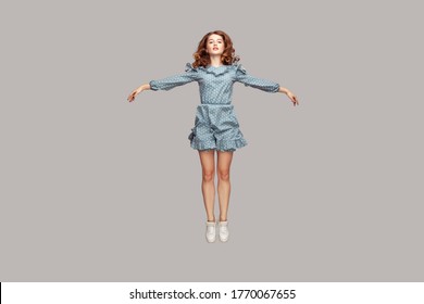 Full length happy calm pretty girl in vintage ruffle dress levitating hovering in mid-air with raised hands as wings, jumping trampoline or flying up. indoor studio shot isolated on gray background - Shutterstock ID 1770067655