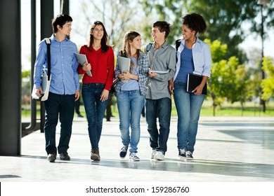 Full length of happy college students walking together on campus - Shutterstock ID 159286760