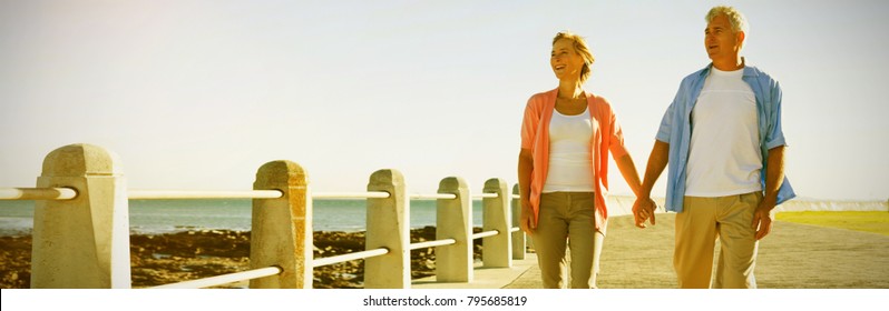 Full length of happy couple walking by sea on footpath - Powered by Shutterstock