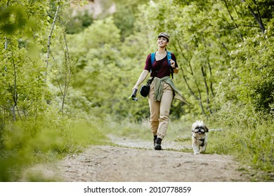 Full Length Of Happy Female Hiker Walking With Her Dog In The Woods. Copy Space.