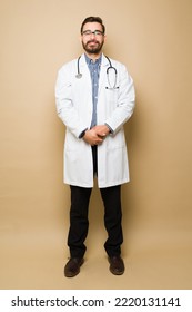 Full Length Of A Happy Male Doctor With A Lab Coat And A Stethoscope Smiling In Front Of A Yellow Background