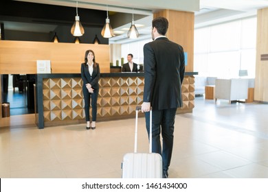 Full Length Of Happy Manager Awaiting For CEO On Business Trip Arriving At Front Desk In Hotel