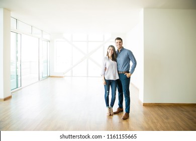 Full length of happy mid adult couple standing in new apartment - Shutterstock ID 1161155665