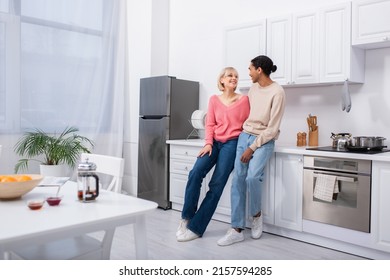 Full Length Of Happy Multiethnic Couple Looking At Each Other In Modern Kitchen