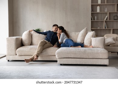 Full length happy relaxed young family couple homeowners or renters lying on big cozy sofa, enjoying carefree leisure weekend time, celebrating moving into new contemporary apartment, tenancy concept. - Shutterstock ID 2047731347