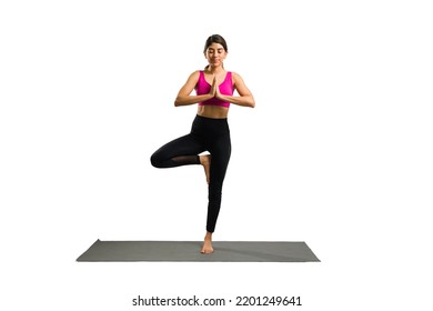 Full Length Of A Happy Relaxed Young Woman Exercising And Doing A Tree Yoga Pose Against A White Background