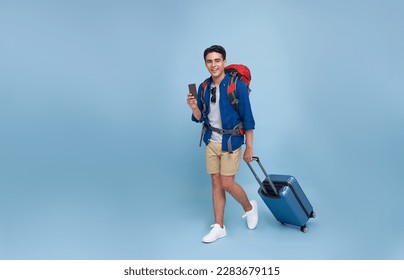 Full length Happy smiling young tourist Asian man walking while holding luggage and showing passport on isolated studio blue background - Powered by Shutterstock