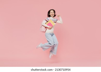 Full length happy teen student girl of Asian ethnicity wearing sweater hold backpack books jump high do winner gesture isolated on pastel plain pink background Education in university college concept - Powered by Shutterstock